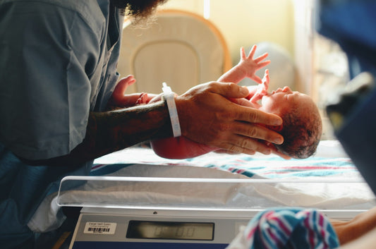Pasgeboren baby wordt gewogen op een babyweegschaal in het ziekenhuis