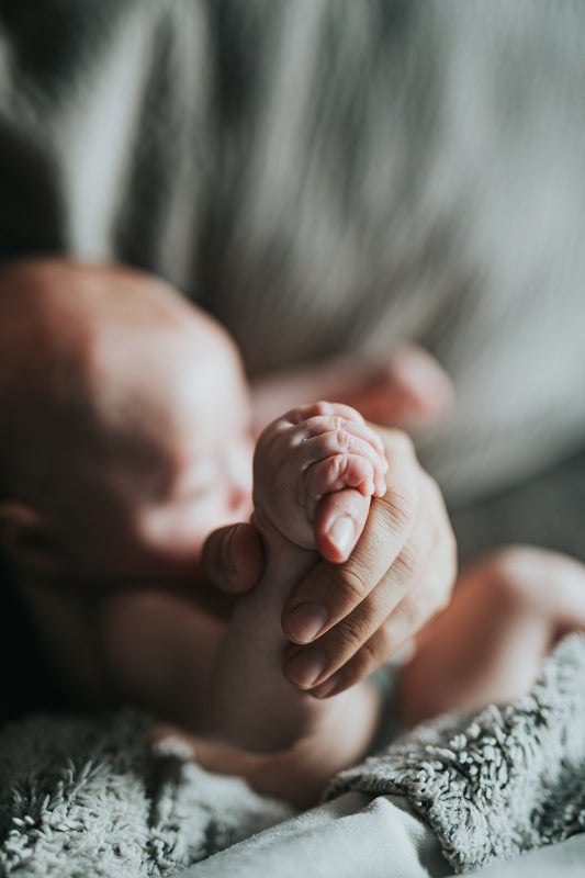 Klein babyhandje houdt de vinger van een ouder vast